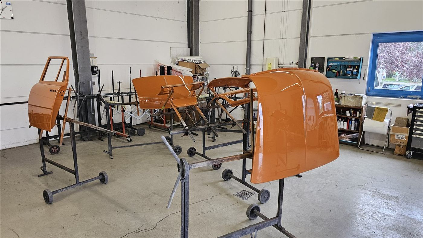 Orange lackierte Türen und Motorhaube auf Lackierständern