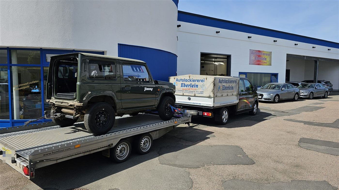 Suzuki Jimny auf dem Autotransporter vor dem Firmengebäude