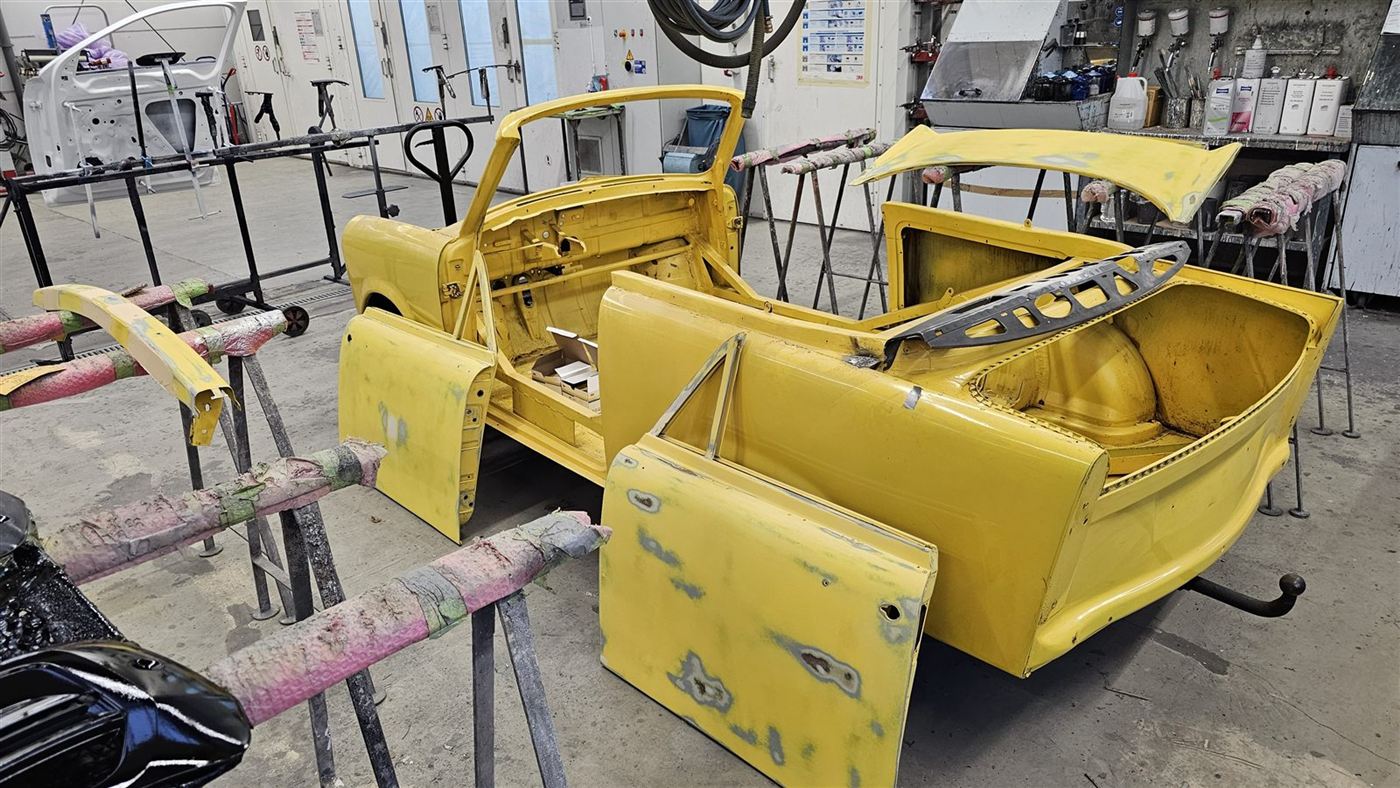 Gelb lackierte Karosserieteile eines Trabant in der Lackierkabine
