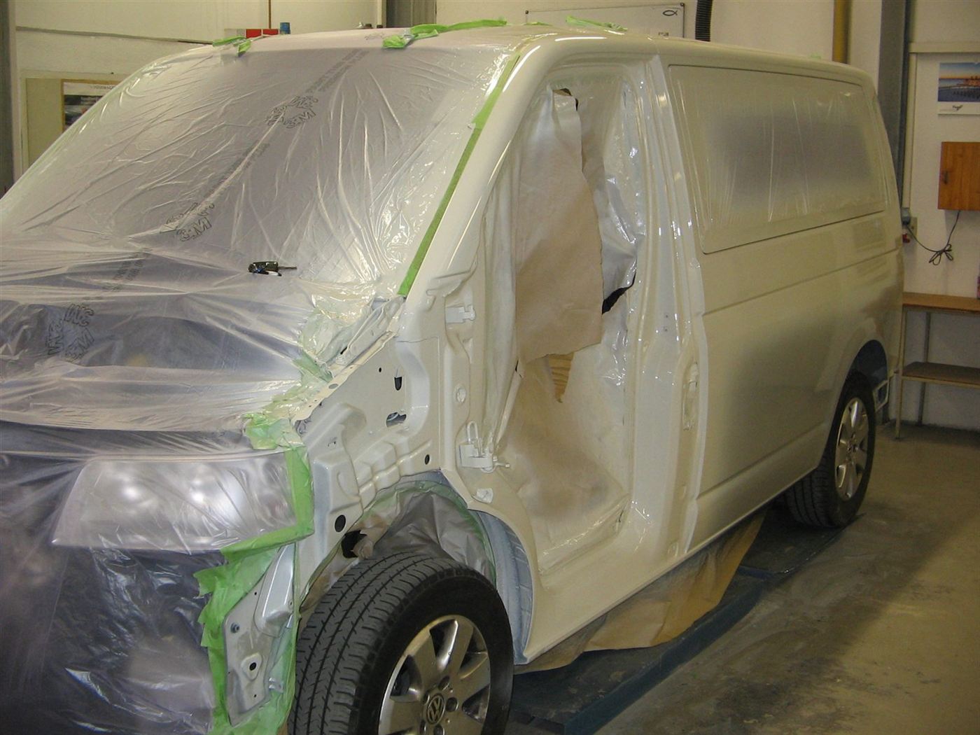 VW Bus T5 mit abgeklebter Front während der Lackierung