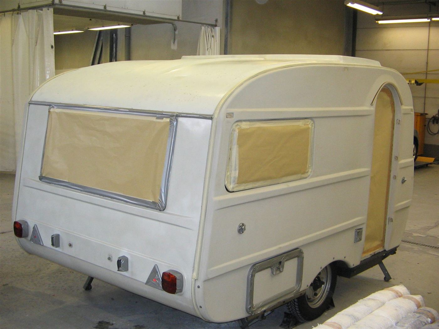Kleiner Wohnwagen mit abgeklebten Fenstern nach der Lackierung